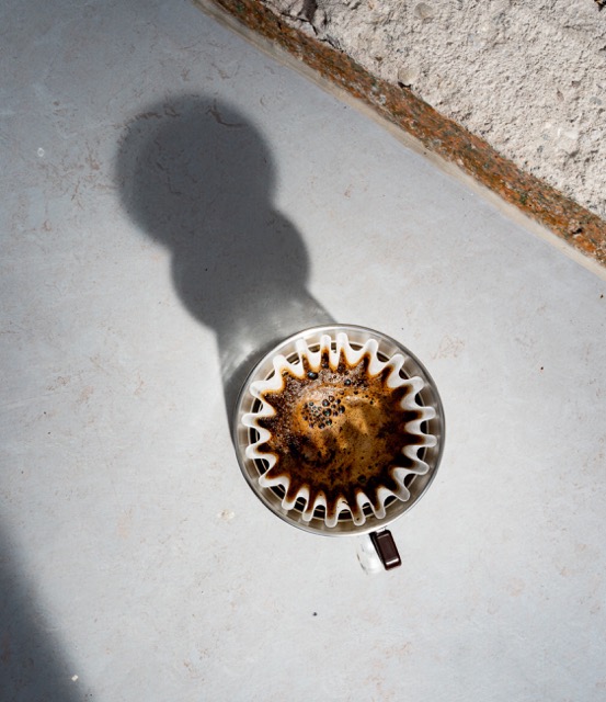 Filterkoffie in v60 in het zonlicht, in sfeervolle omgeving van koffiebranderij.